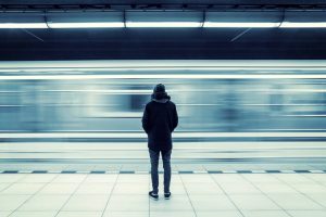 Person waiting at a train station while a train passes